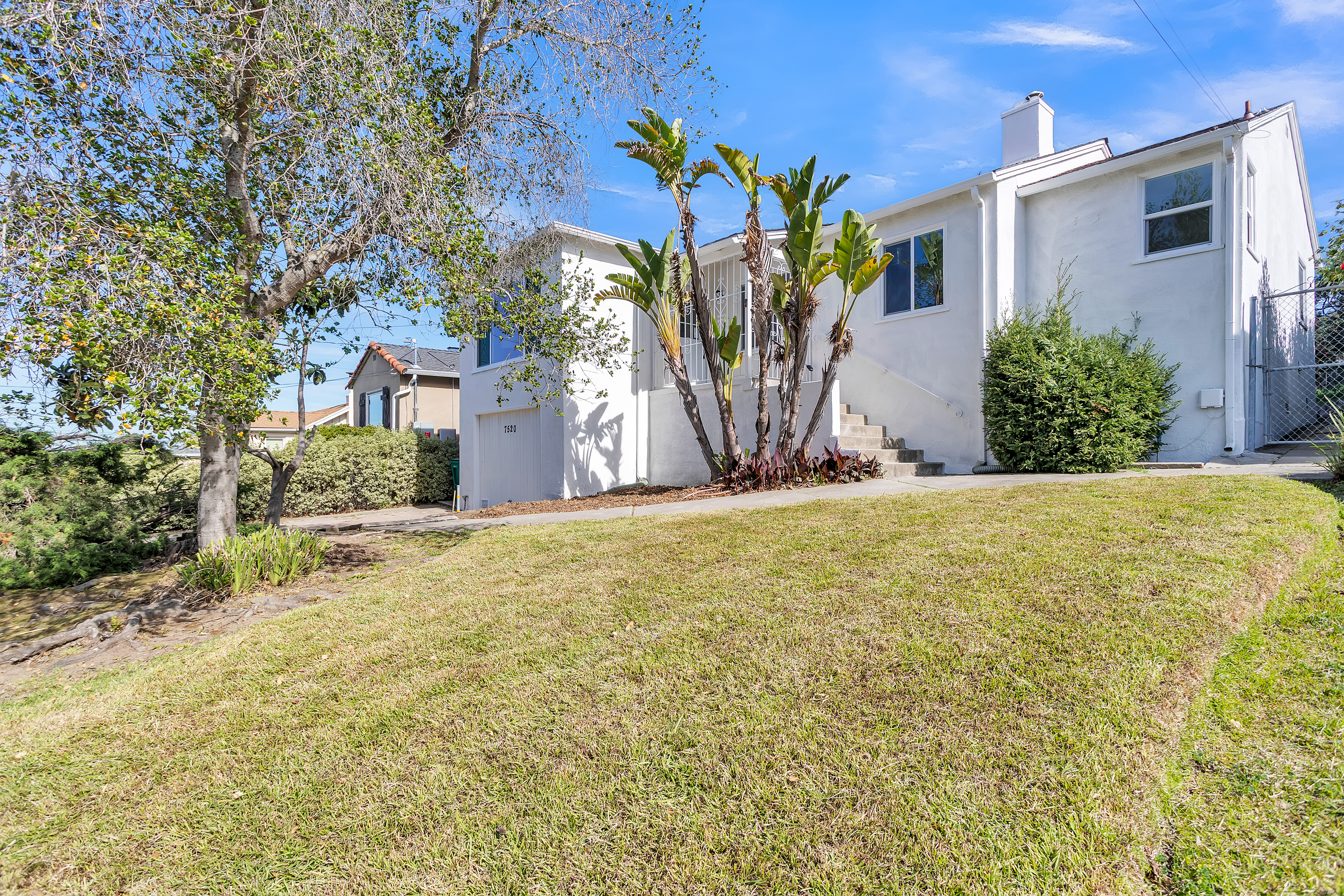 Sunkist Drive exterior after renovation — freshly painted white with clean landscaping and green lawn