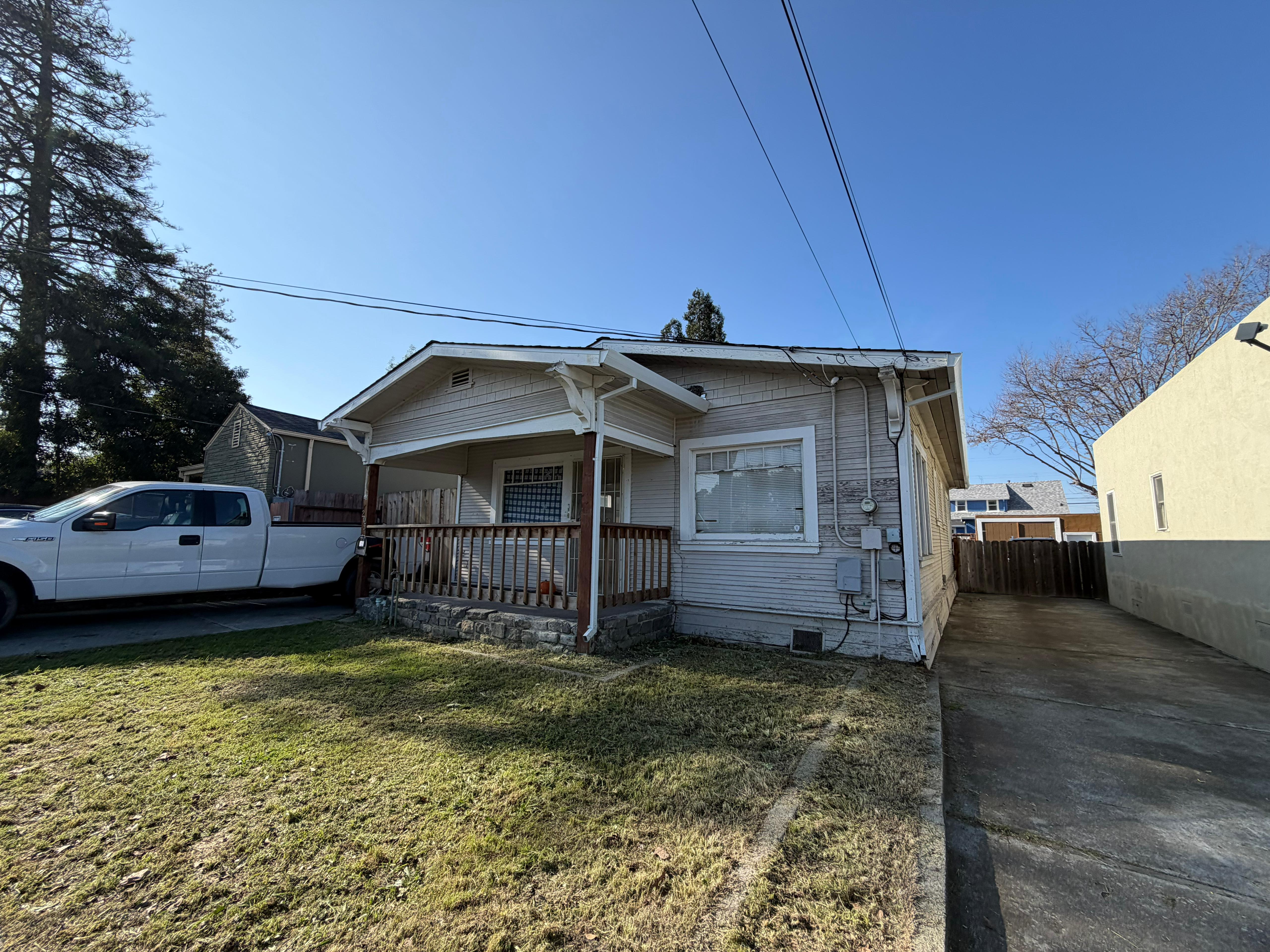 Exterior of an Oakland property before acquisition — showing original worn condition with aged siding and landscaping in need of attention.